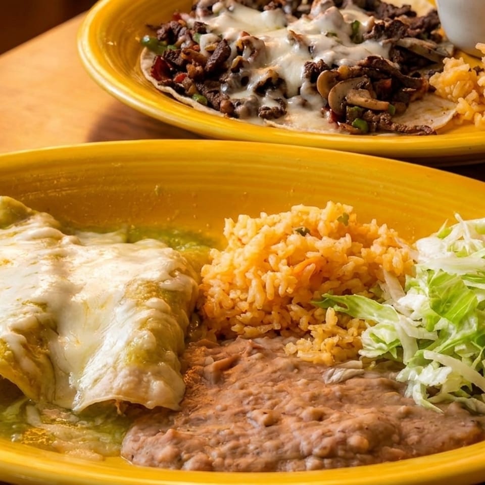 Two yellow plates of Mexican food: enchiladas with rice, beans, and lettuce, and a steak dish.